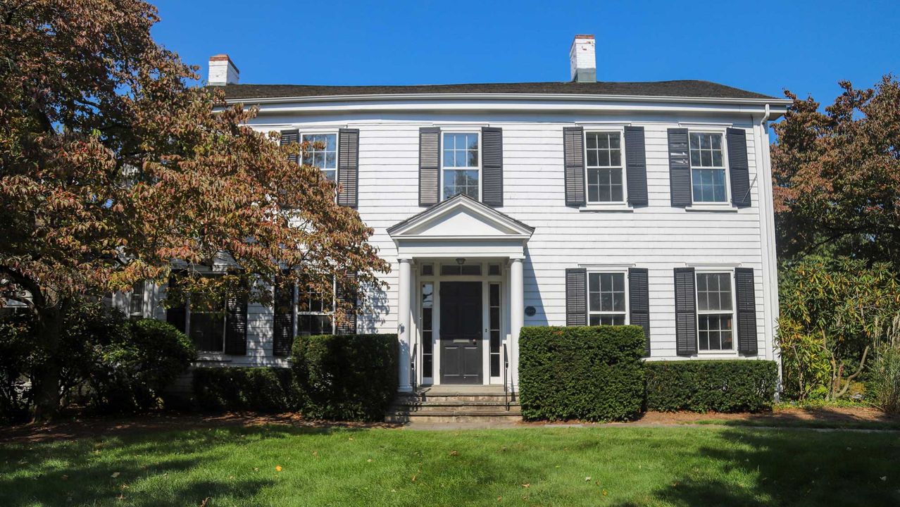 The white clapboard Town House with black shutters and a columned entrance.