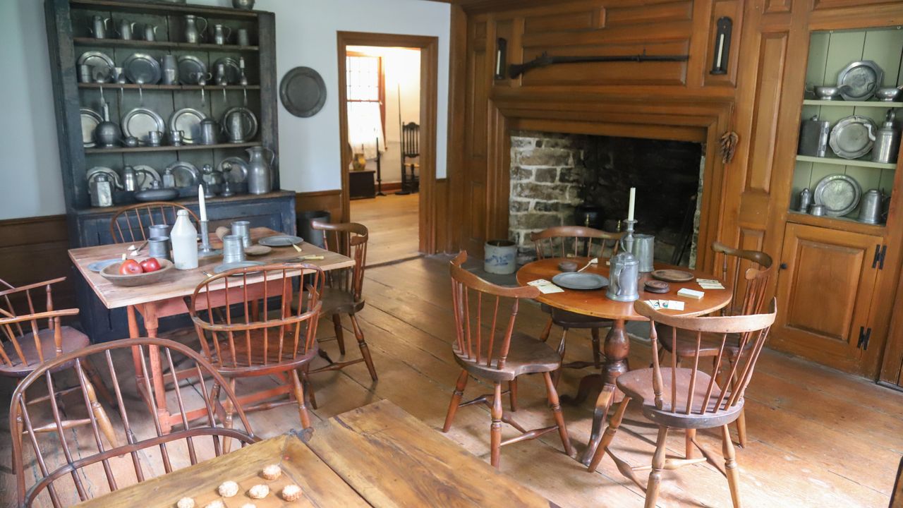 The historic tavern with a stone fireplace and tables set with pewter.