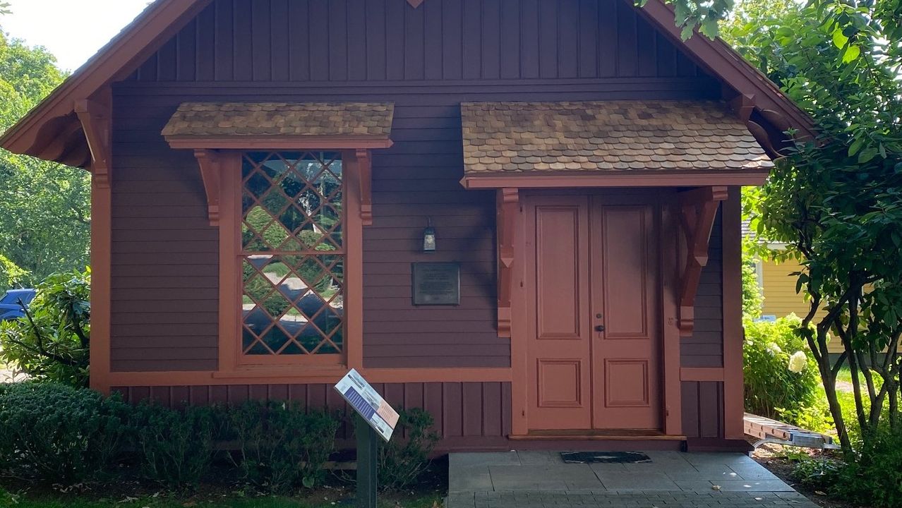 The brown wooden Rogers Studio with ornate trim and a steep gabled roof.
